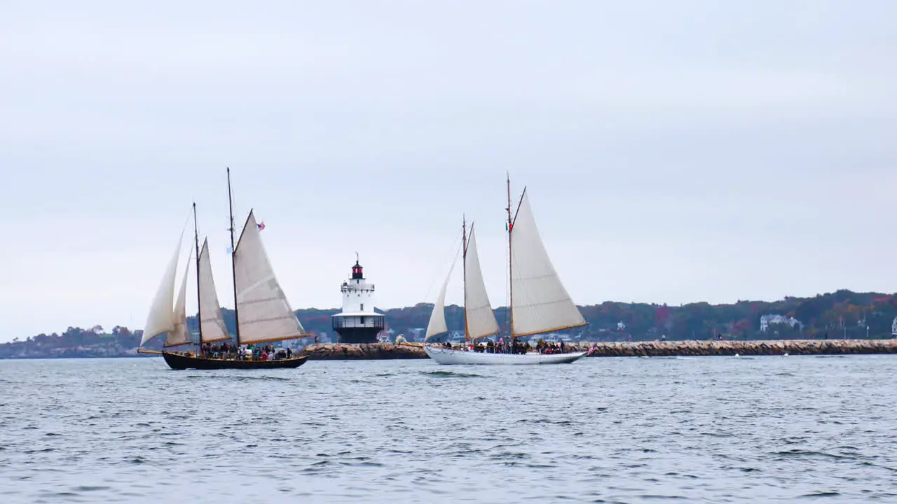 Gorgeous wide shot of a pair of Schooners traveling in front of Spring Point Ledge Lighthouse in Casco Bay Maine