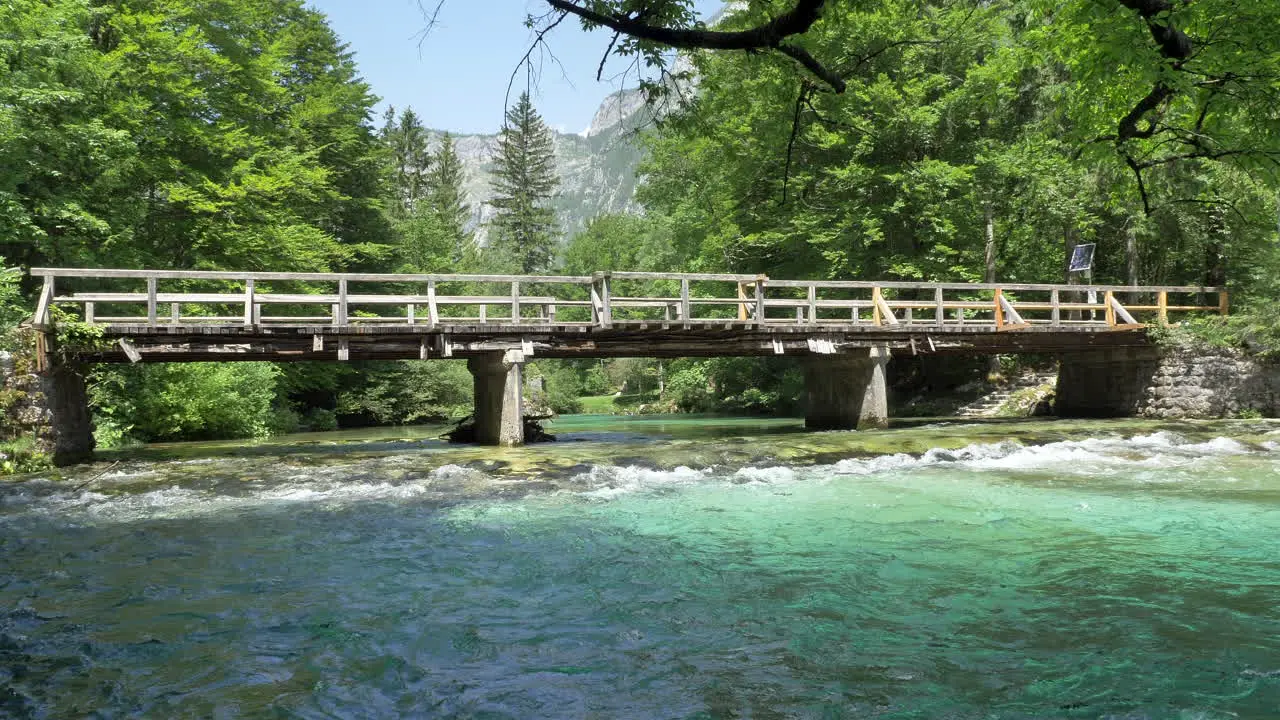 An old wooden bridge in Slovenia crossing the river with clear water and beautiful colors