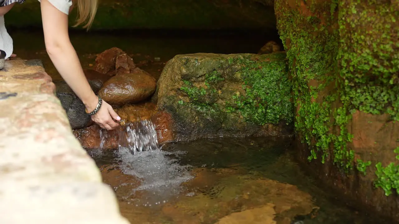 Woman Drinks Natural Water from A Small Stream Coming Out of A Cave