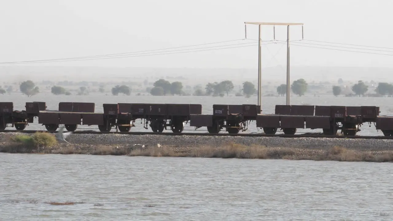 Empty Rail Wagons On Railway Tracks With Floodwaters Either Side In Sindh With Bird Flying Past