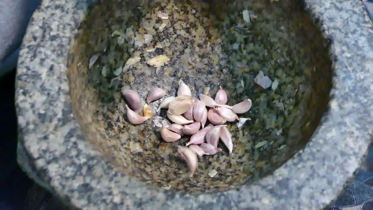 Add Garlic and Red Chili Pepper Into Stone Mortar Close Up Slow-Motion Handheld