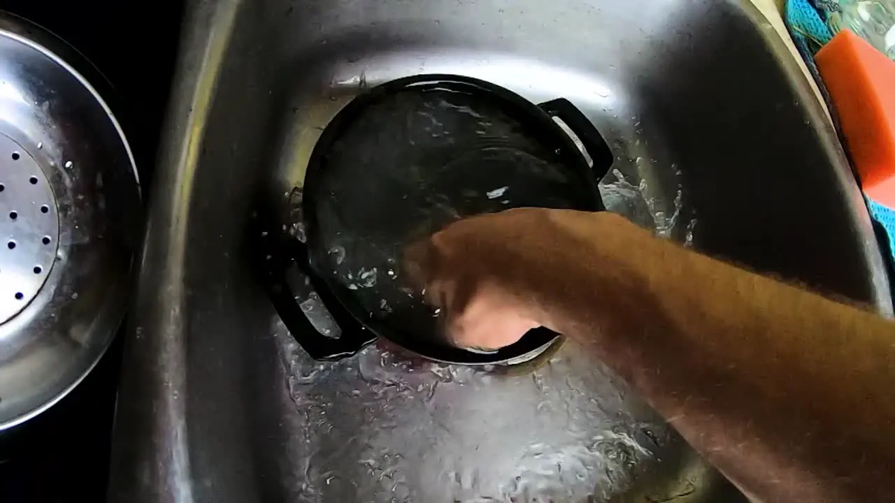 SLOW MOTION Cleaning a small pot with a hand in a kitchen sink