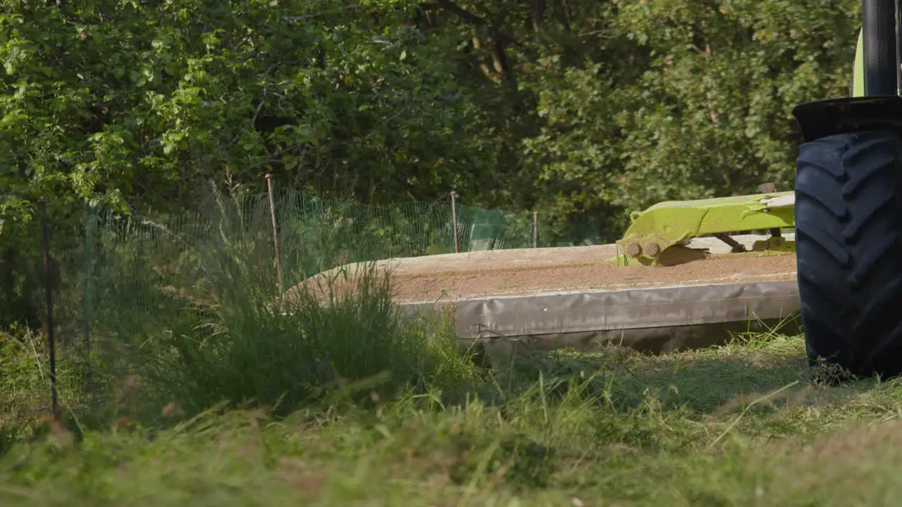 Heavy tractor cutting grass on sunny day slow motion view