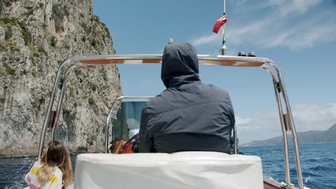 A traditional boat is sailing along Capri's coast in Italy during a sunny and col day in spring