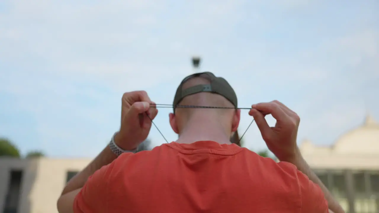 View Behind Adult Male Who is Tightening Lanyard Around Back Of Neck