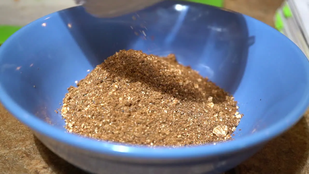 Dumping Brown Spices in Blue Bowl Slow Motion Close Up