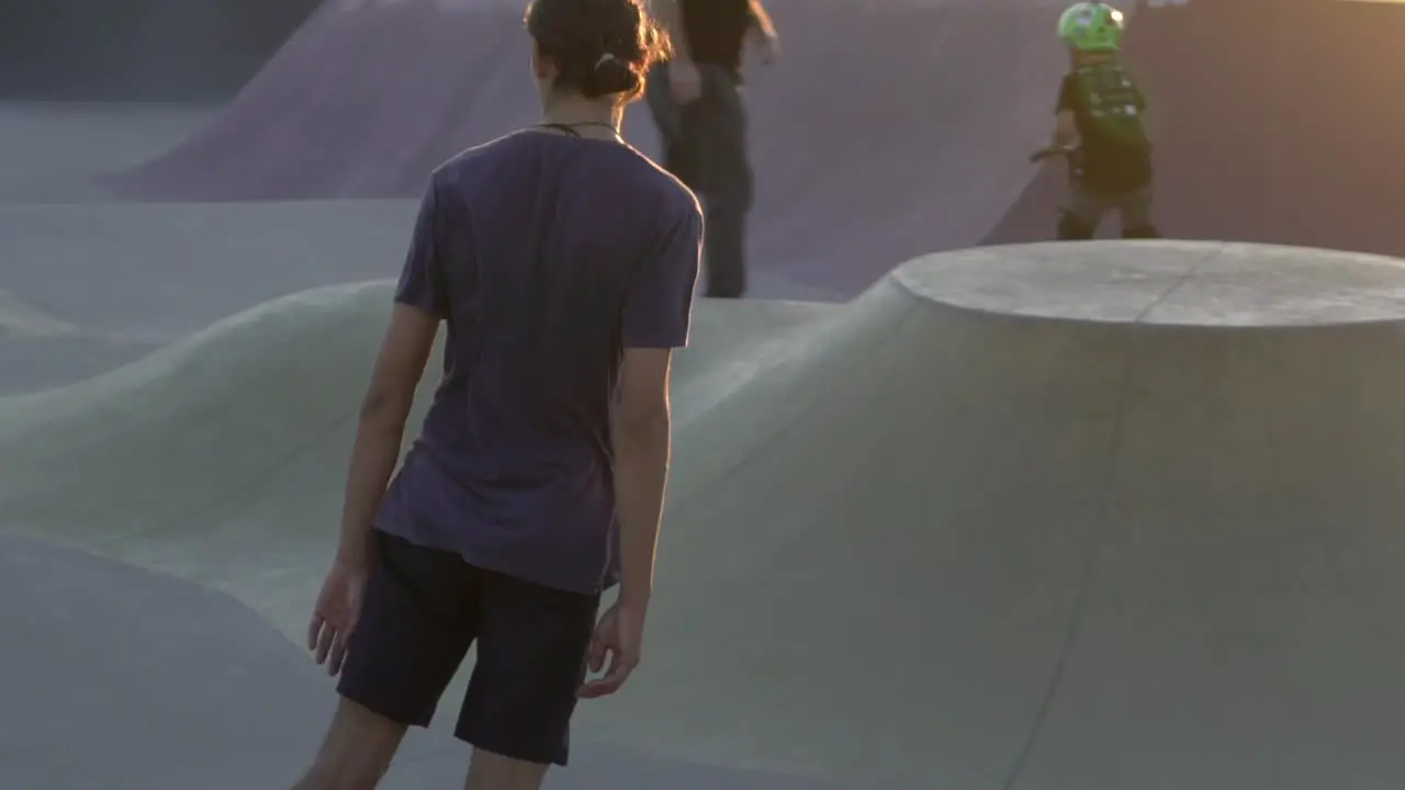 Slow motion shot of boy on skateboard riding at park during sunset