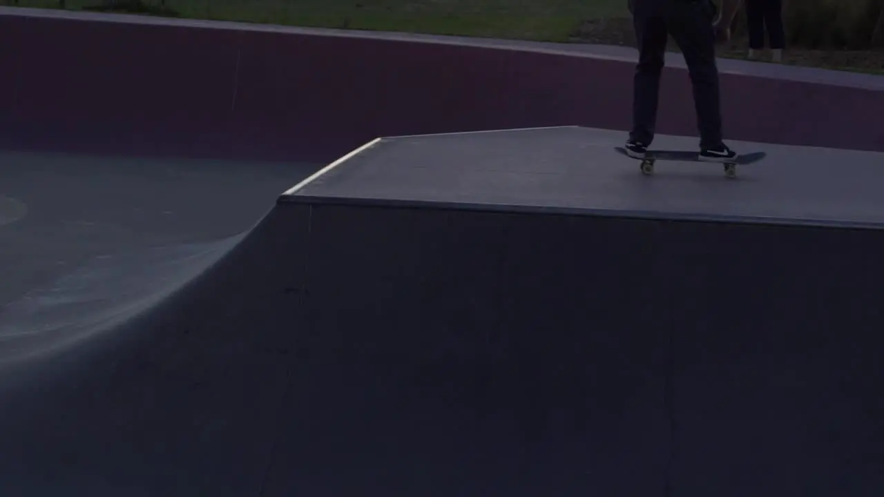 Slow motion shot of boy doing on ollie on rail at a skate park skateboarding during sunset