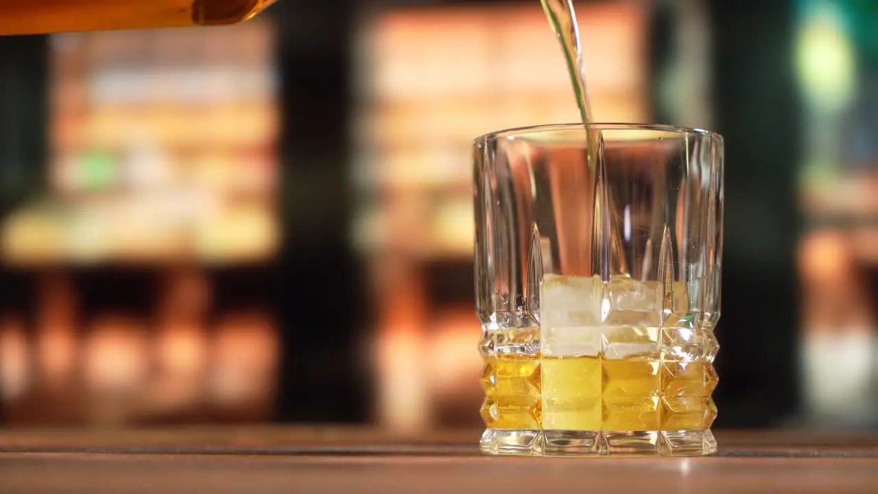 Whiskey being poured into a glass with ice 4K