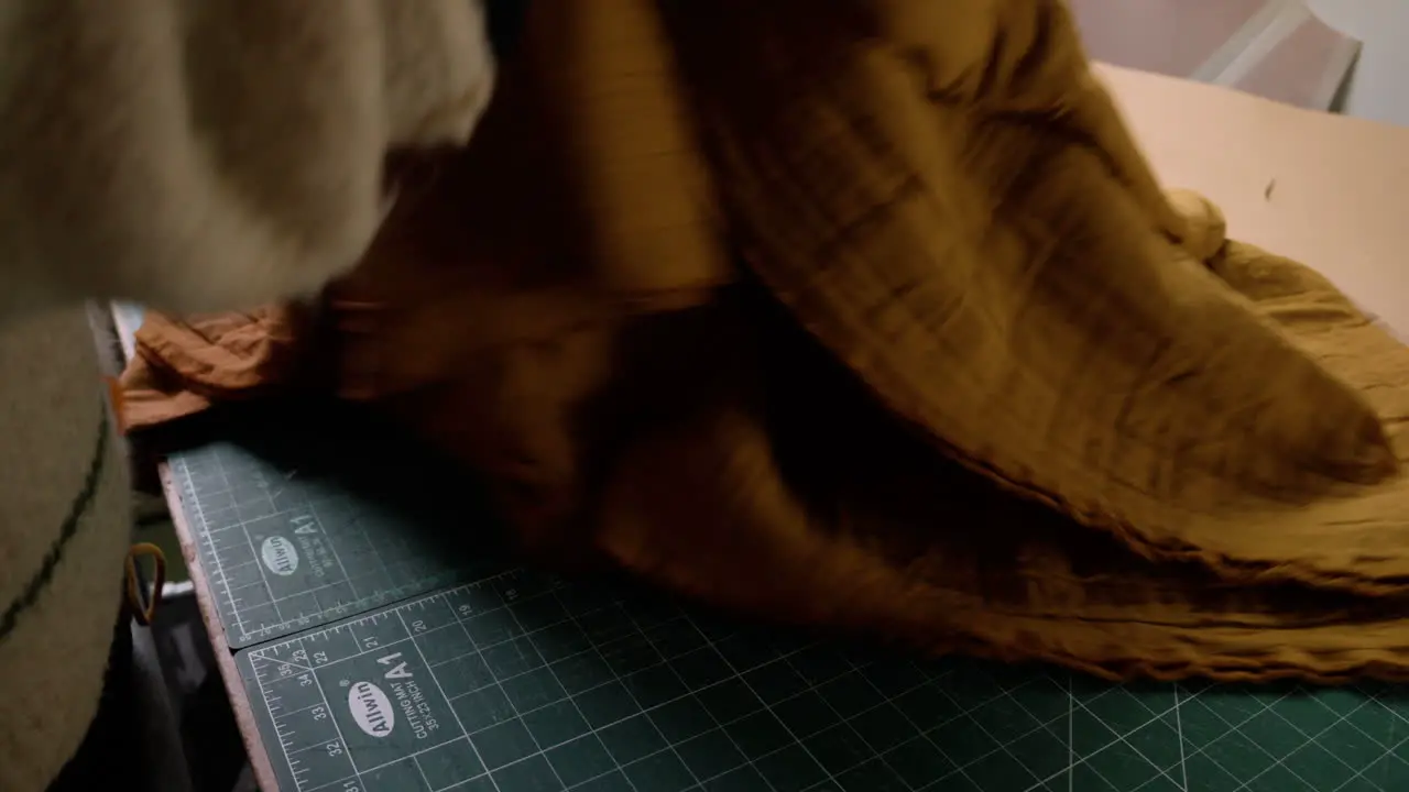 Seamstress putting fabric down in preparation for cutting material in fashion design studio