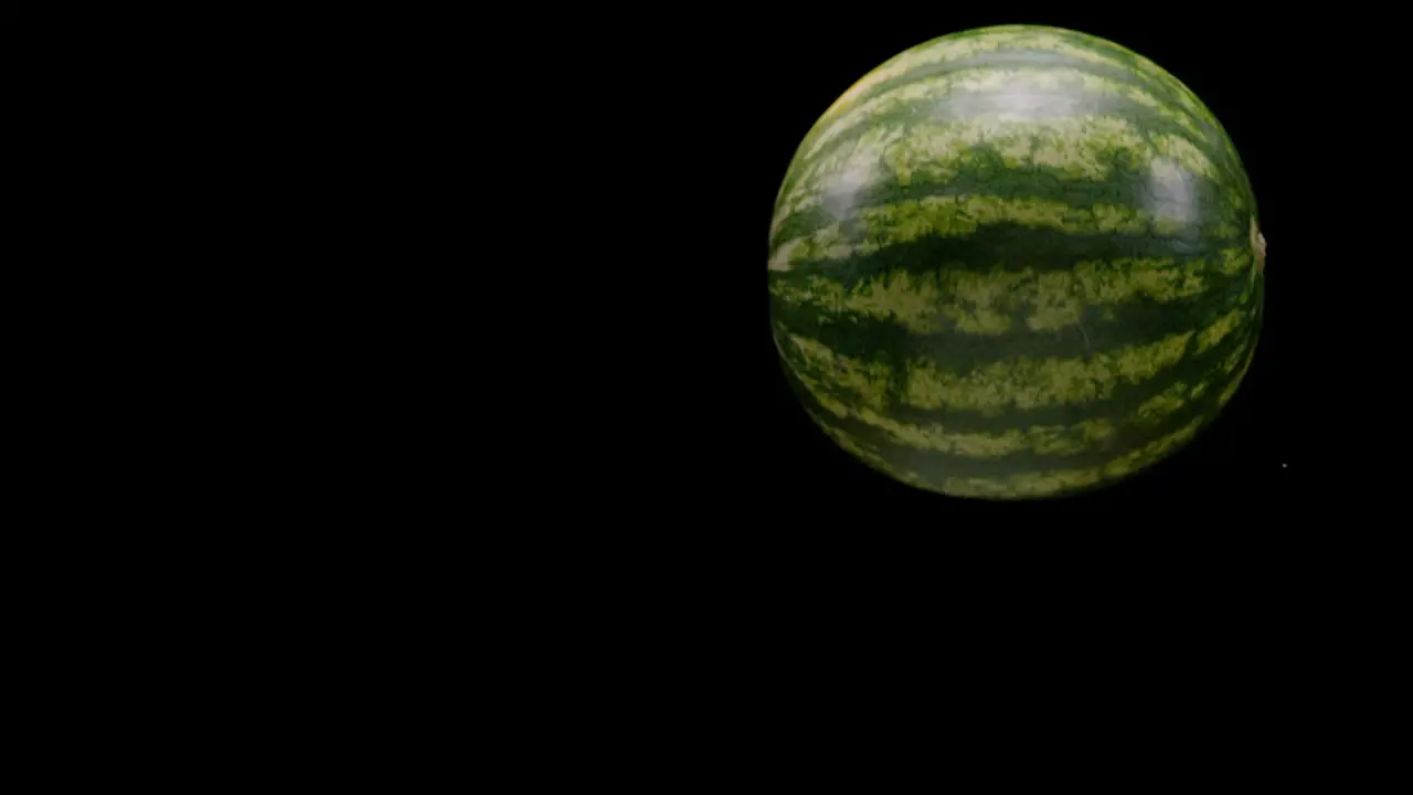 Watermelon falling and rotating isolated on black background slow motion