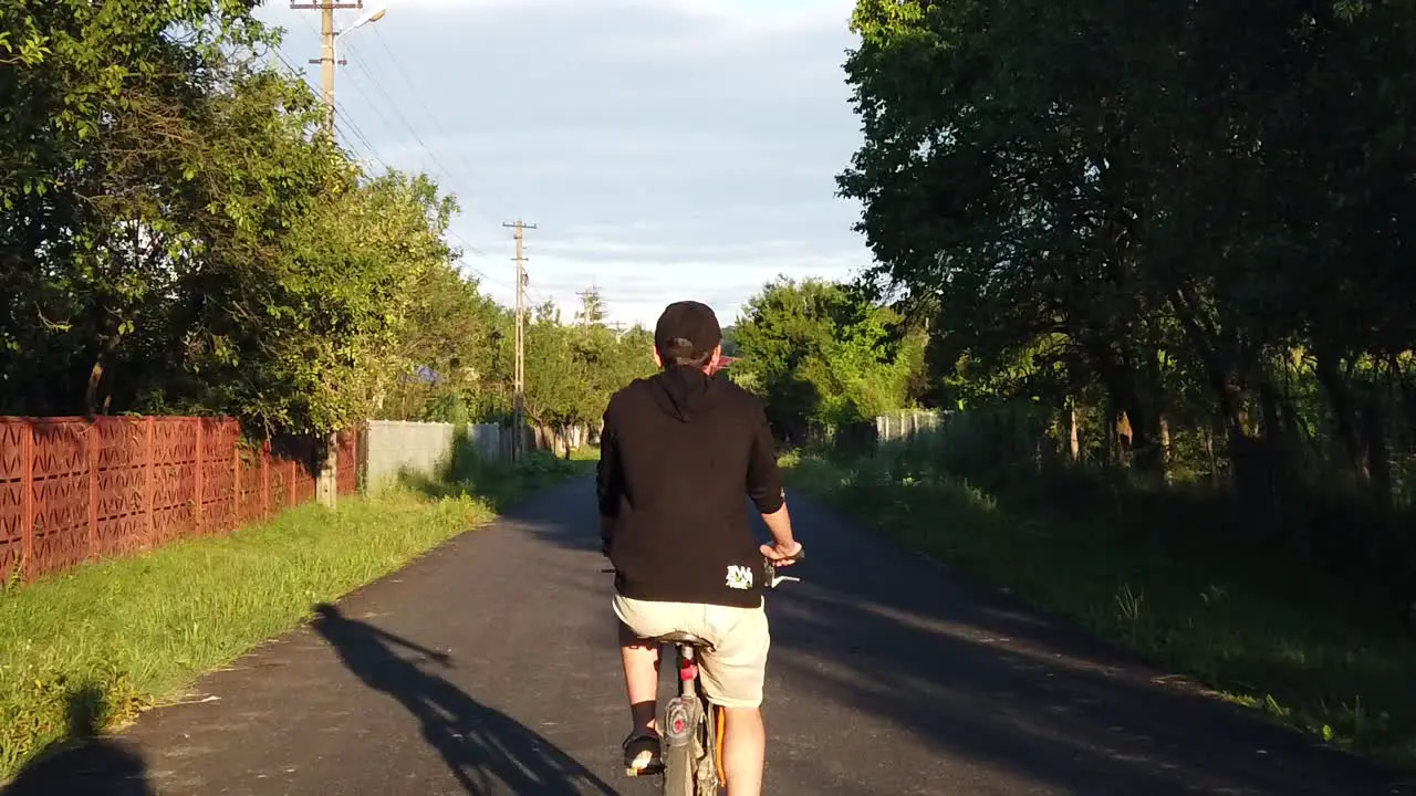 Moreni Romania 13 July 2020  Guy wearing black riding bike on a country road at sunset slow motion