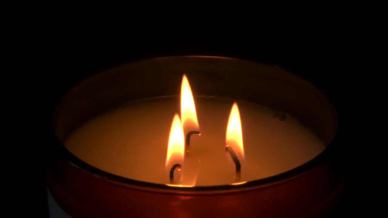 Slow mo three candles burning with dark background