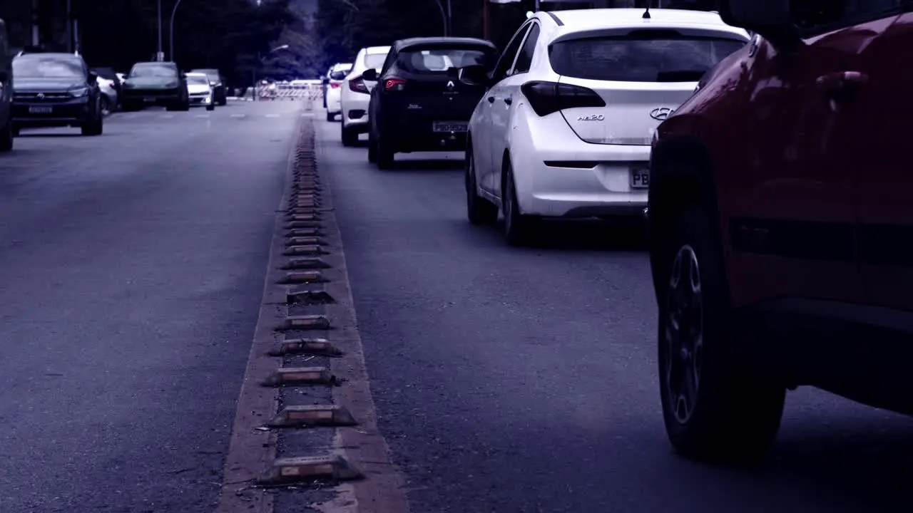 Cars driving on asphalt road in Brazil in slow motion desaturated gloomy filter effect