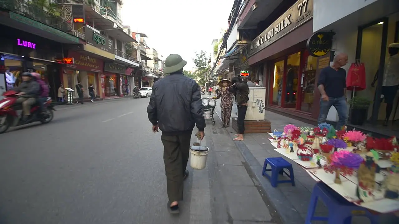 Man Walking with Bucket down Vietnamese Street