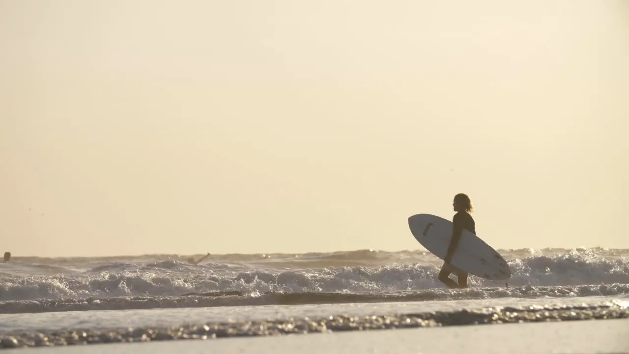 Man Carrying a Surfboard into the Sea