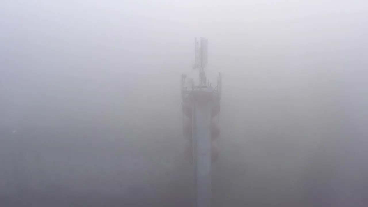 Telecommunication broadcasting antennas in a fog on water tower aerial orbital view