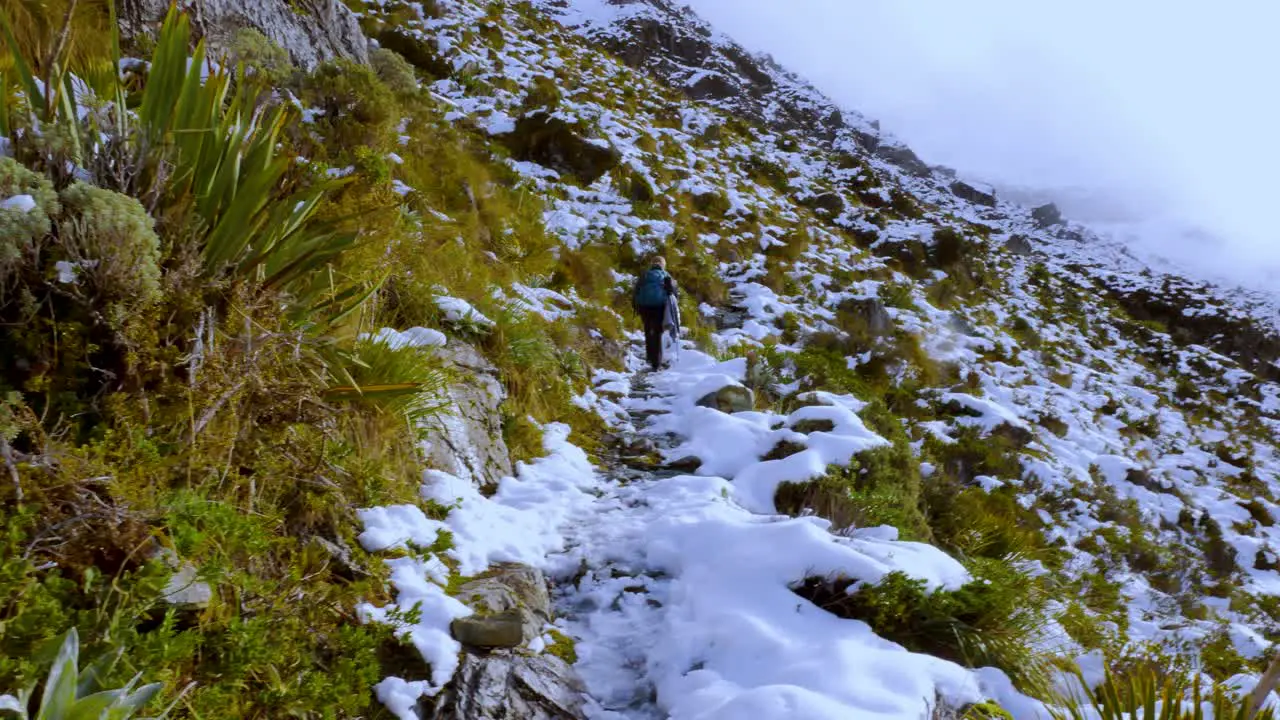 Solo trekker hiking the snow covered steep slopes of mountains