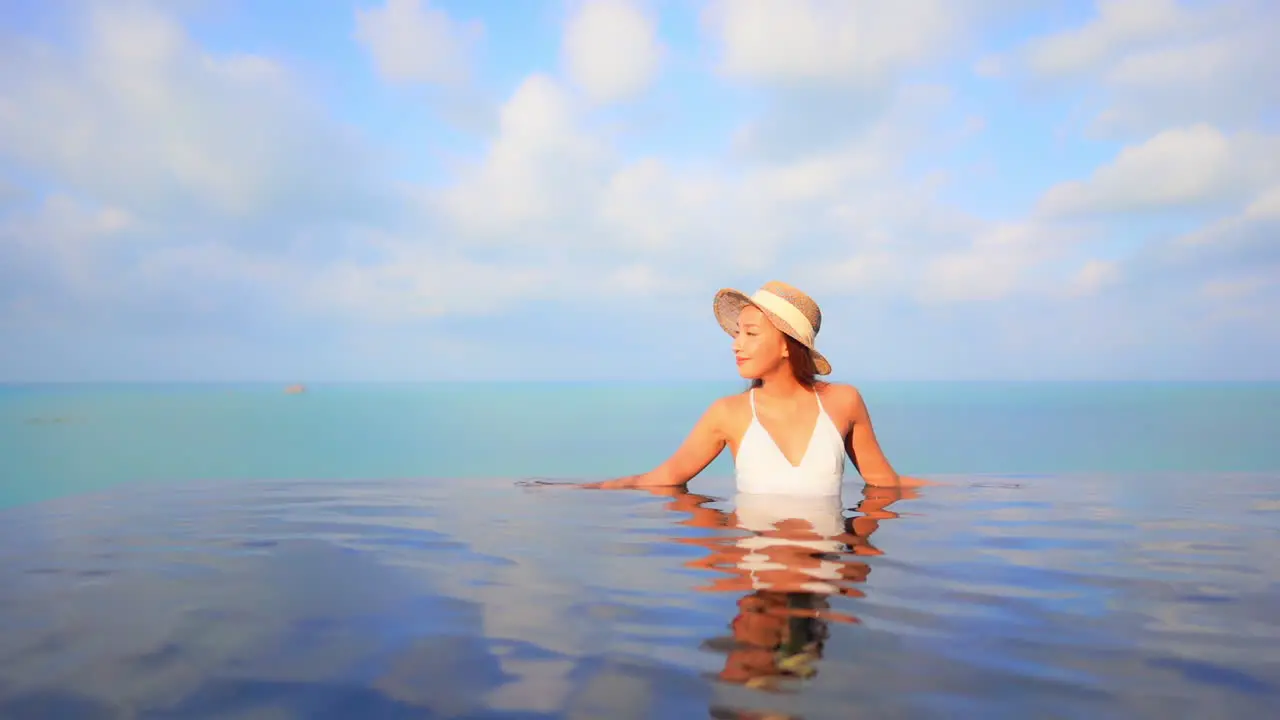 A sexy young woman relaxes in an infinity-edge pool