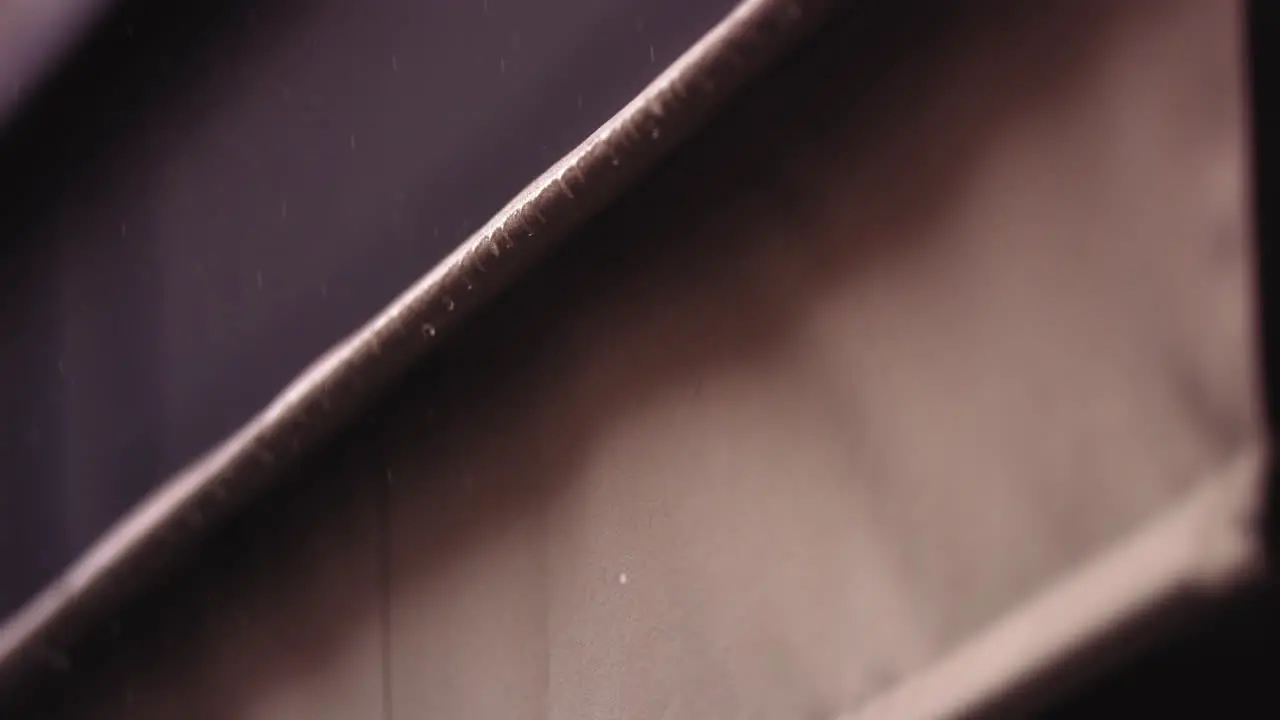 Slow motion footage of raindrops falling off the edge of an awning of a restaurant