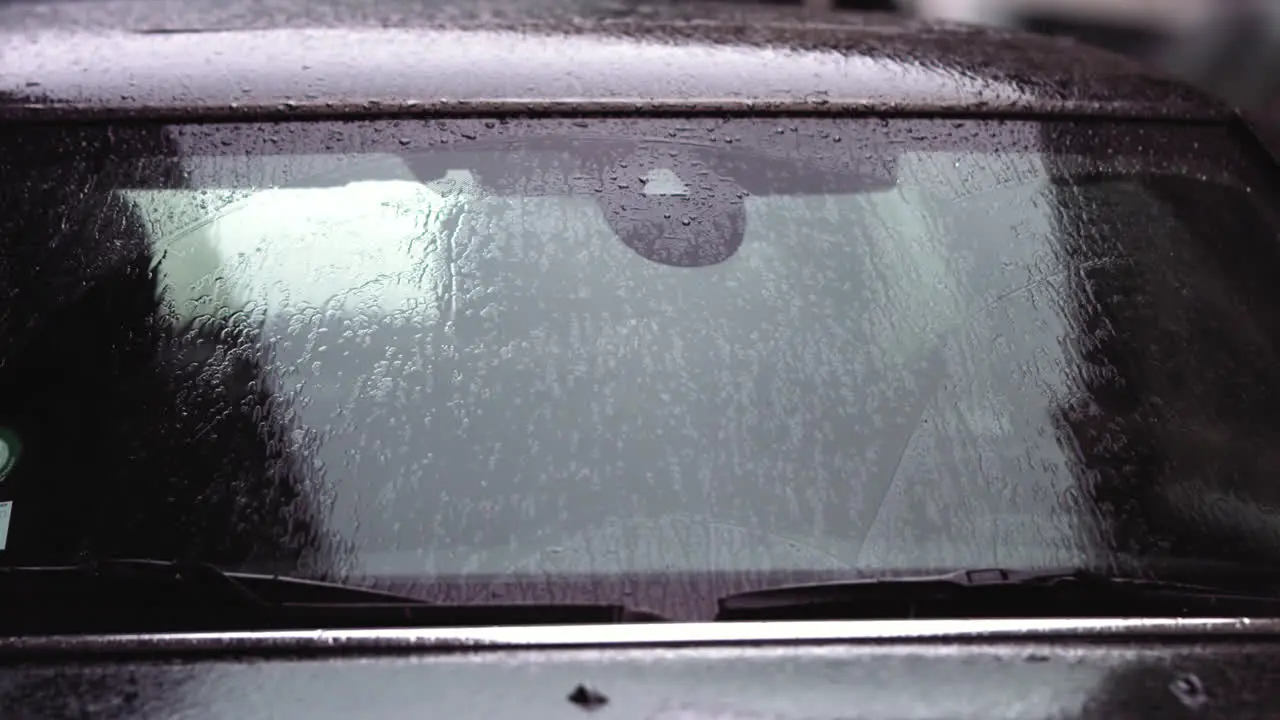 Super slow motion footage of raindrops hitting the the windshield of a car