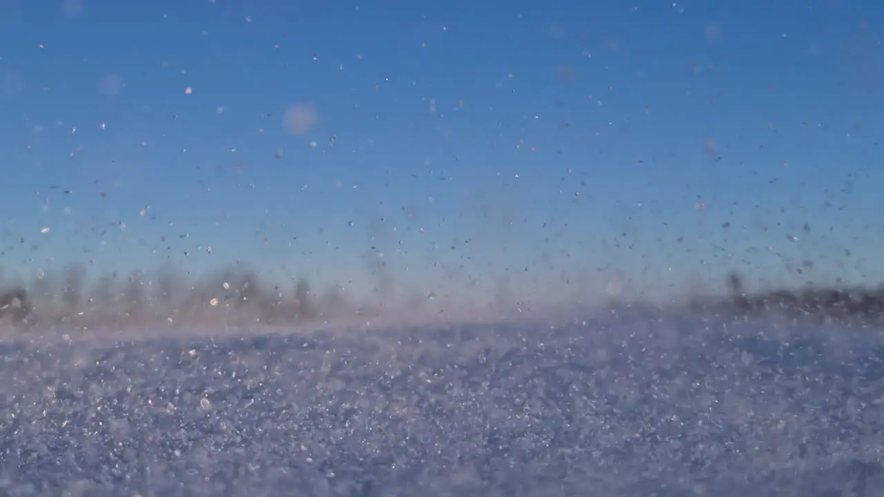 Low angle shot of winter snow ice crystals in wind on blue sky sunny day