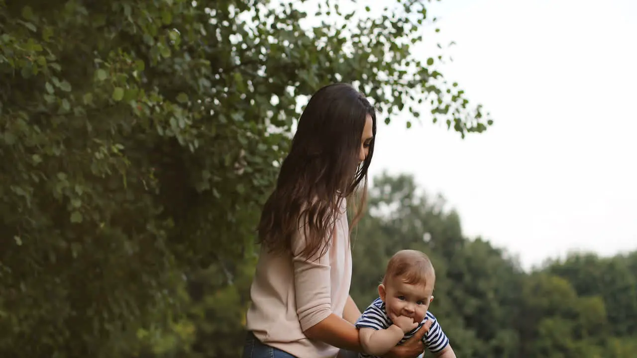 Happy Young Mother Holding Her Cute Baby In Arm Swinging As Airplane Outdoors