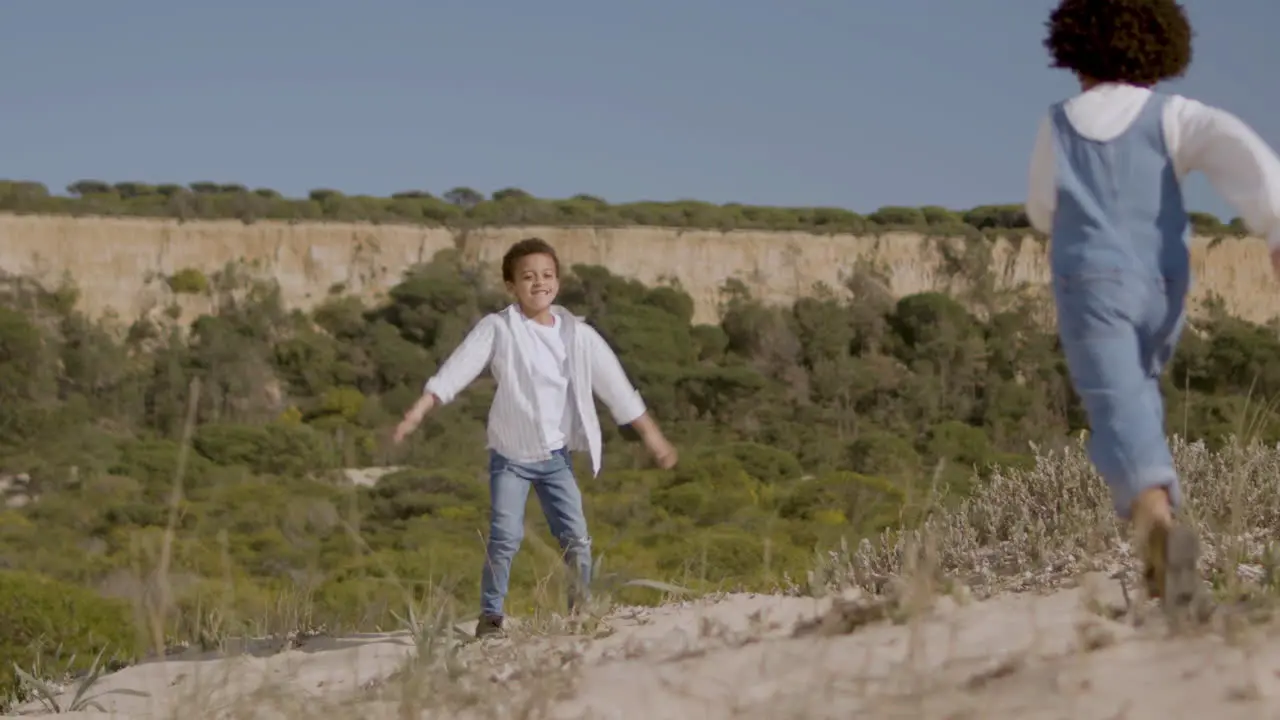 Little American Girl Running And Hugging Her Brother While Enjoying Vacation Time In Natural Park On A Sunny Day