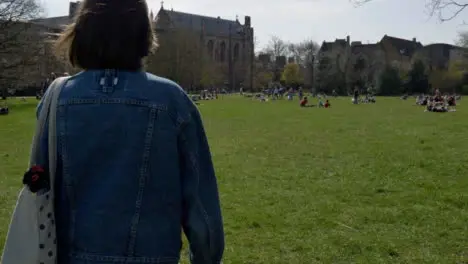 Tracking Shot Following Young Woman Walking Through Park 