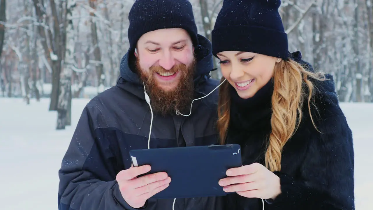 Young Couple Walks In The Park Use A Tablet