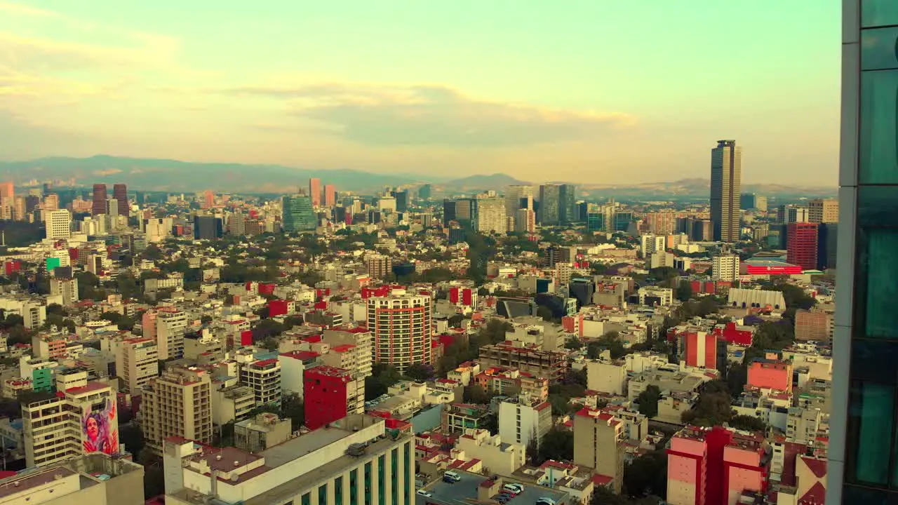 Drone revealing cityscape behind tall building urban neighborhood Mexico City morning light clear sky