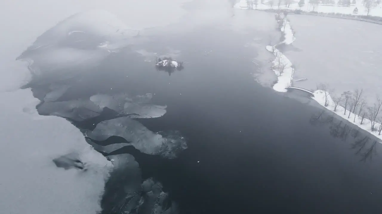 Drone shot of winter scene with birds on the iced surface of frozen river