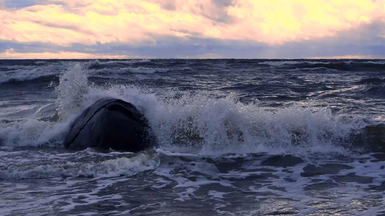 Waves in the sea during a thunderstorm at sunset large stones on the sea shore