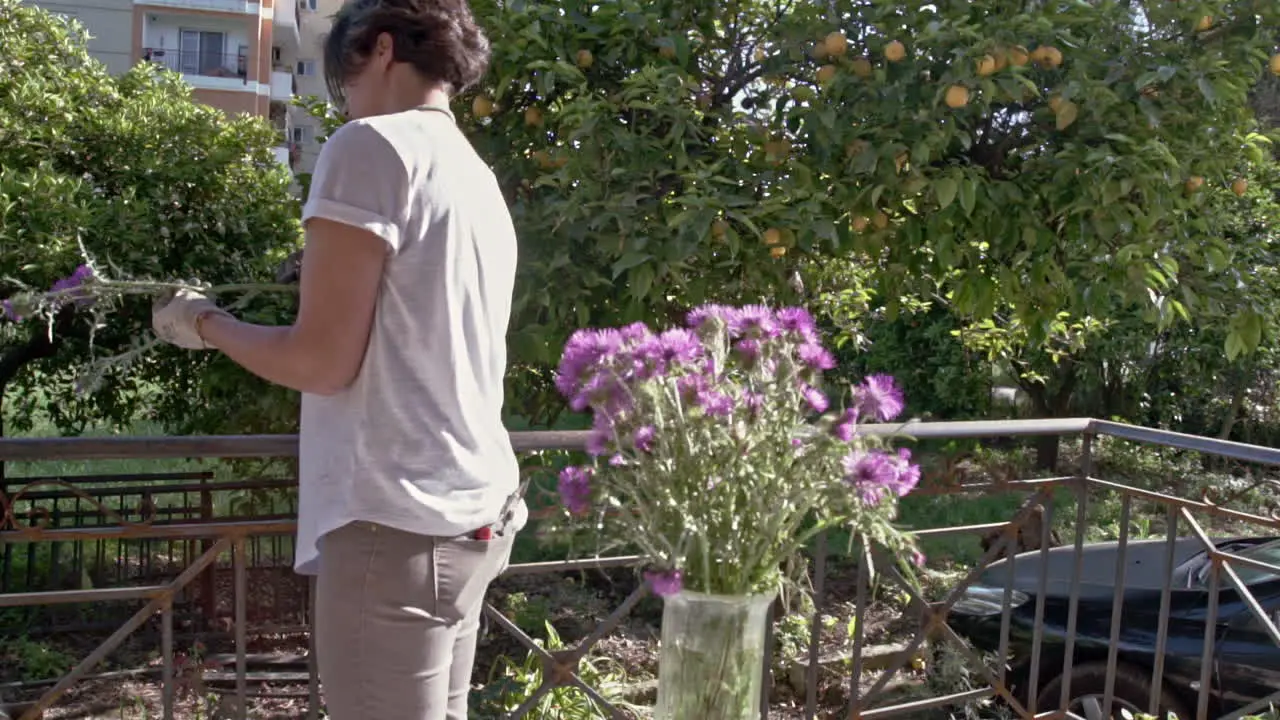 Woman decorates a vaze with wildflowers at a porch of a countryhouse 60fps