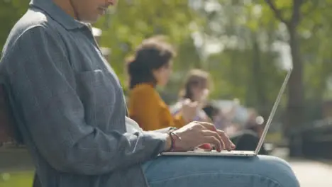 Close Up Shot of Man Using Laptop Sitting on Park Bench