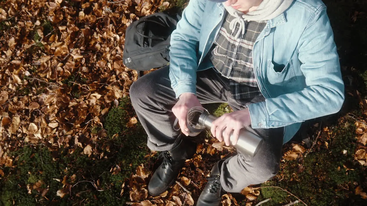 young man pouring coffee in his cup on a sunny autumn day