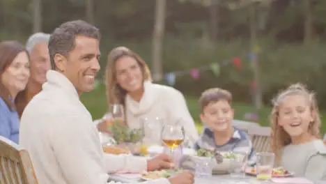 Tracking Shot of Family at Outdoor Dinner Table Smiling 