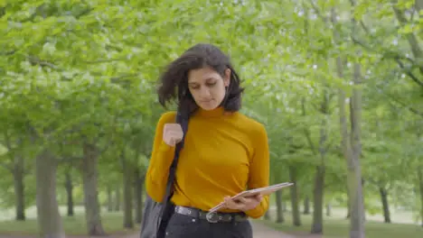 Tracking Mid Shot of Female Student Walking Through Tree Lined Path