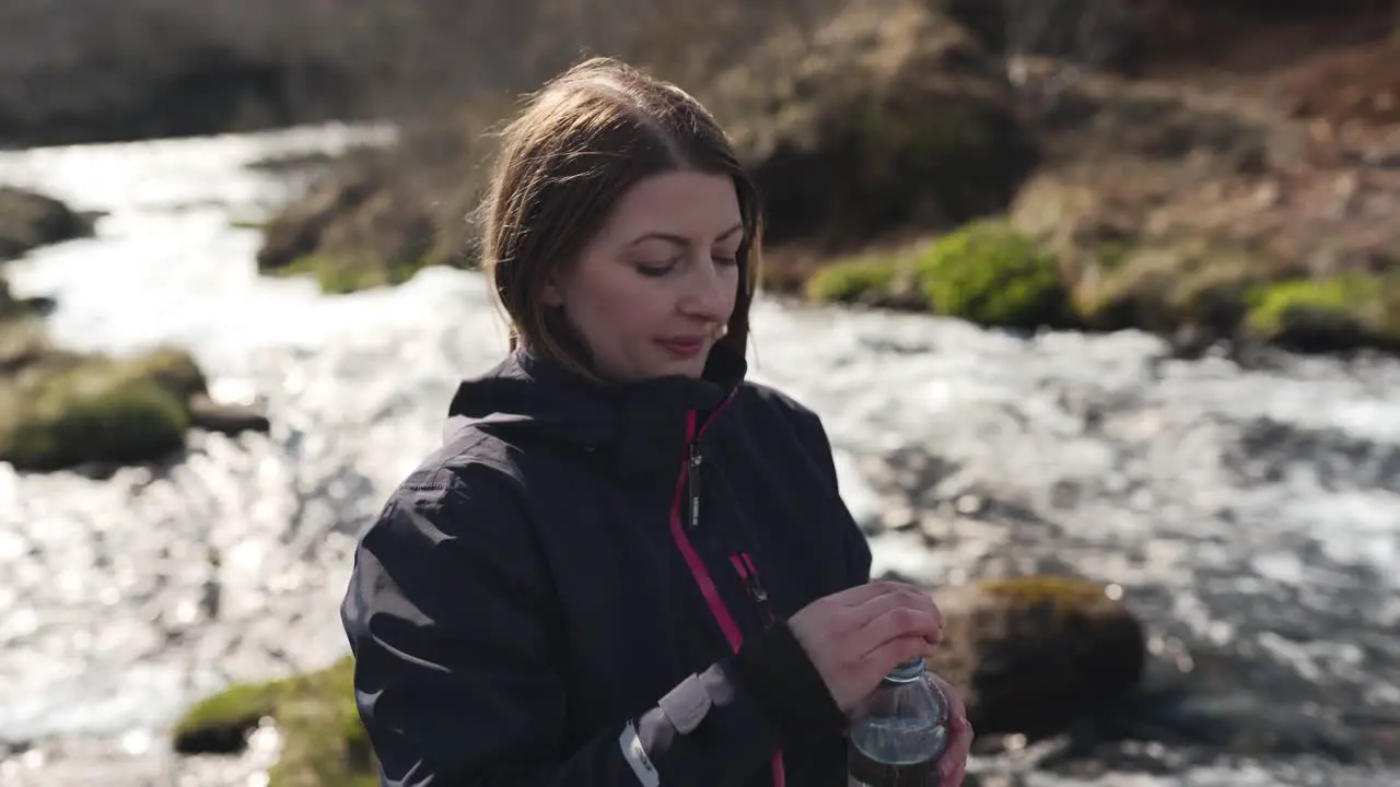 Female hiker just filled her bottle with fresh water from a river coming from Bruarfoss in Iceland and taking a sip of it