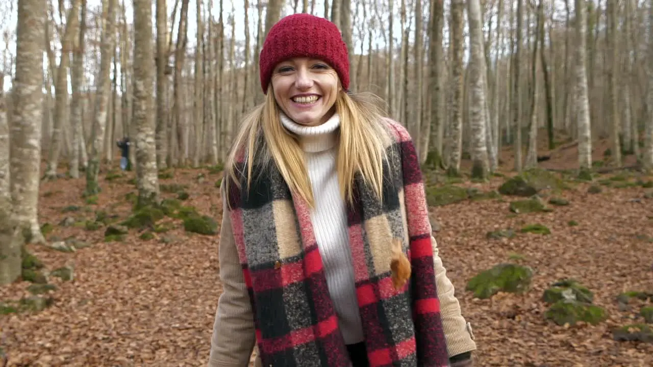 Young smiling happy woman throws dry leaves towards camera