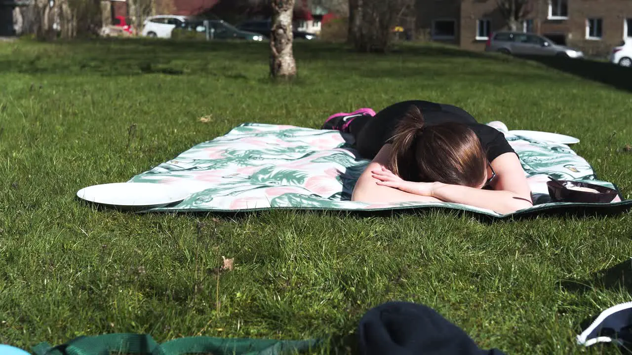 Woman laying on a blanket in the sun after a hard workout totally exhausted-1