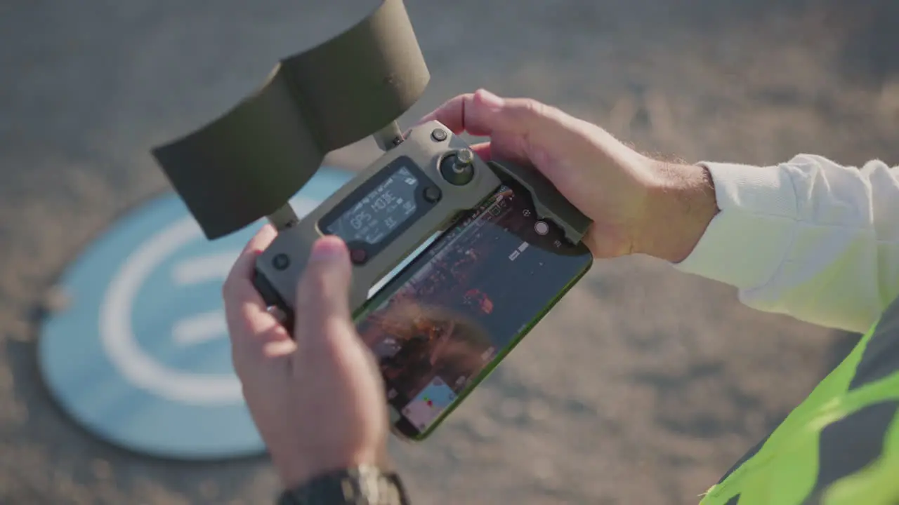 A man stands outside and hold a controller and looks at it