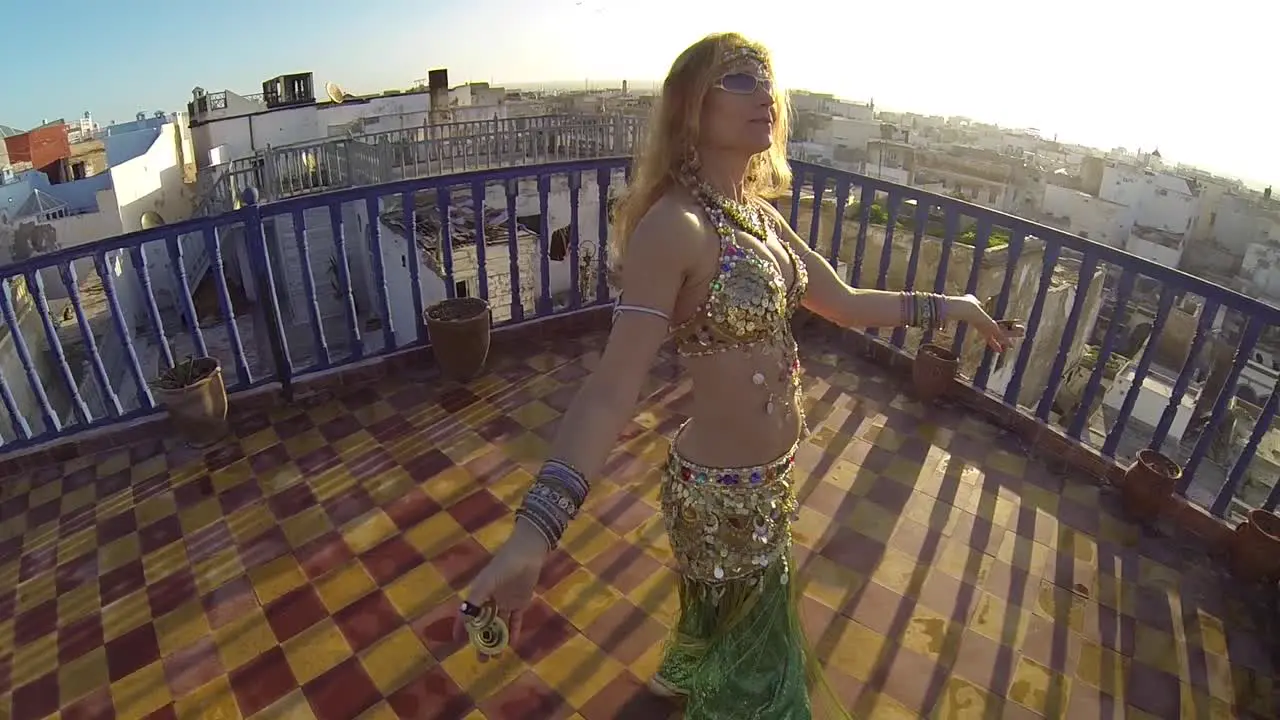 Belly dancer rejoices at sunset as she dances on a rooftop in Morocco