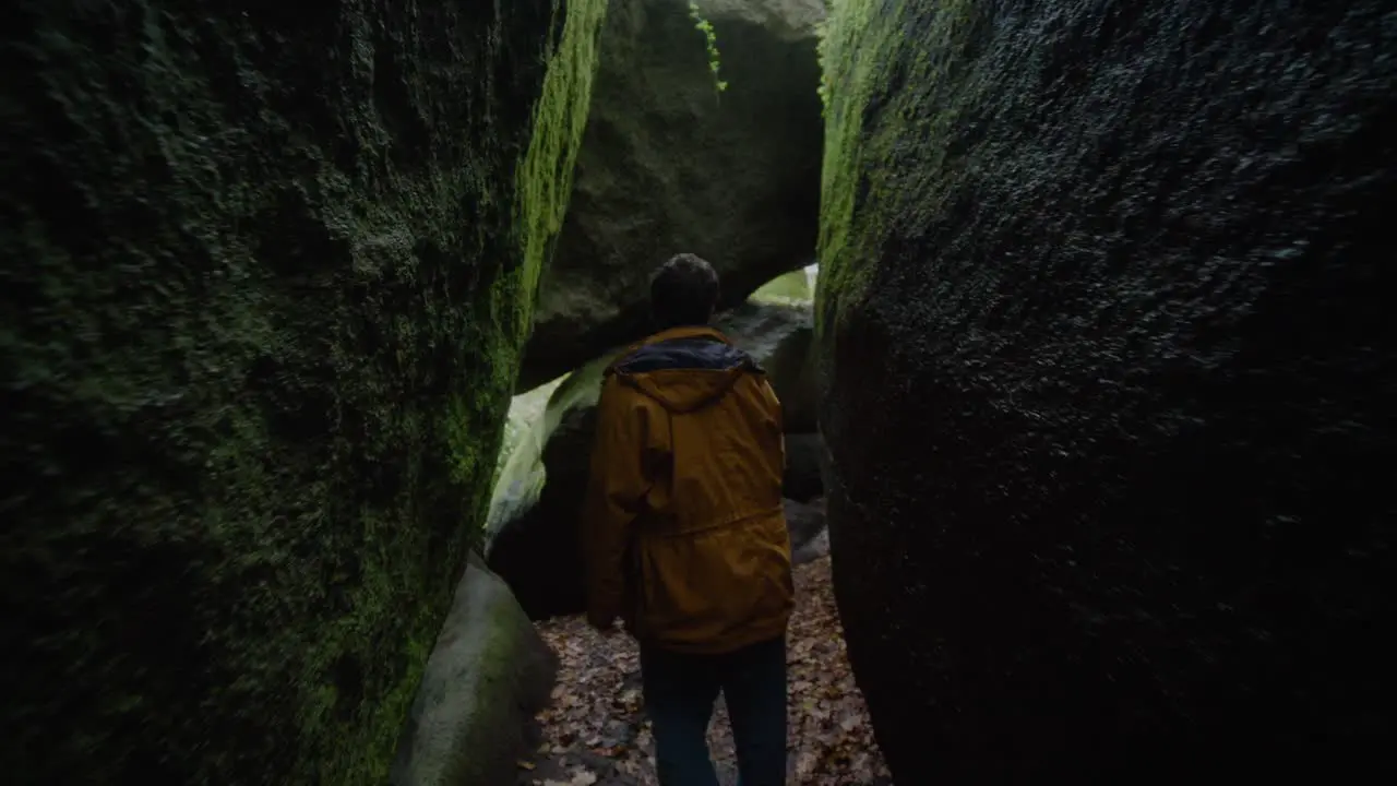 Adult Male Exploring In Between Large Moss Covered Boulders