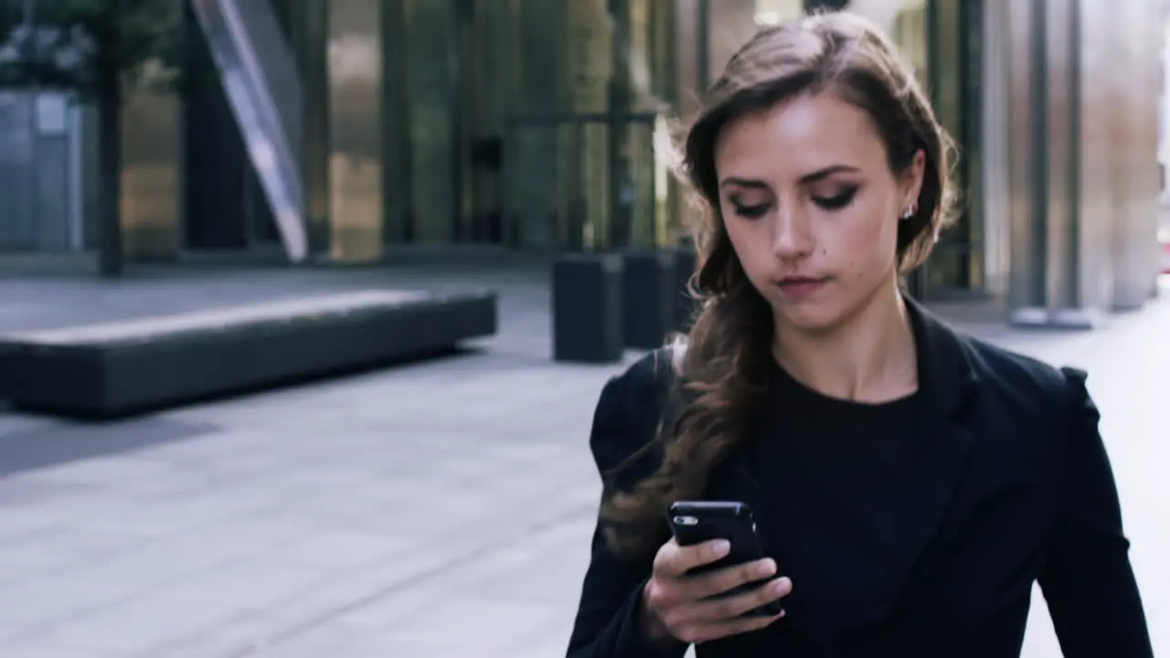 Attractive business woman commuter using smartphone walking in city of london