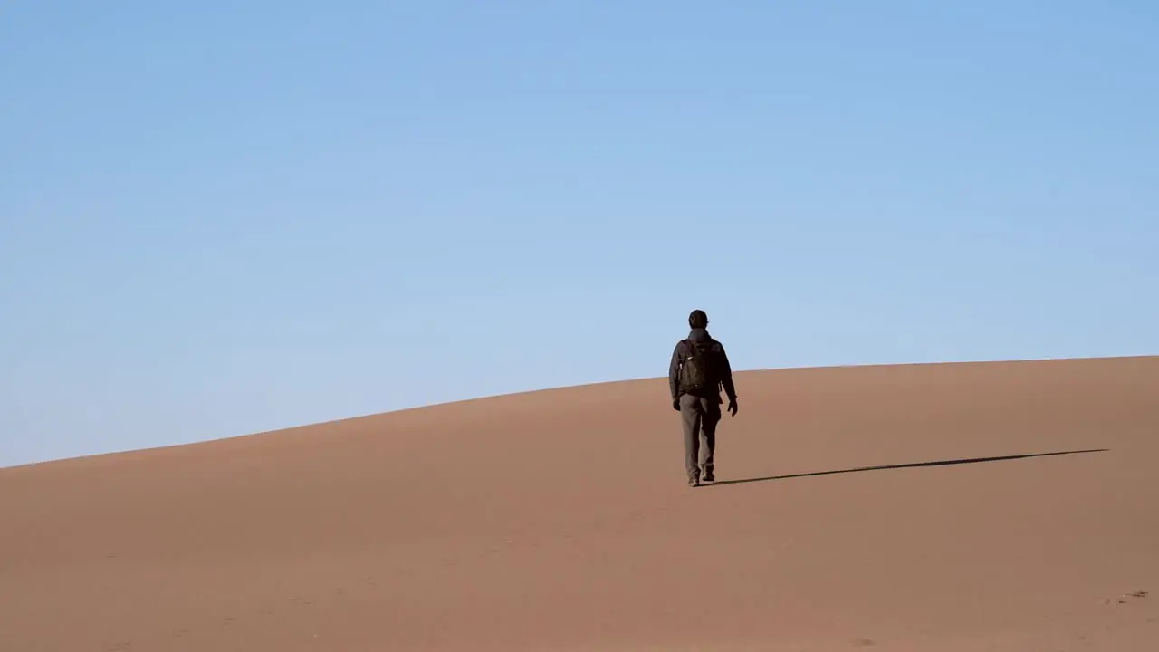 Man walking on sand dunes in slow motion