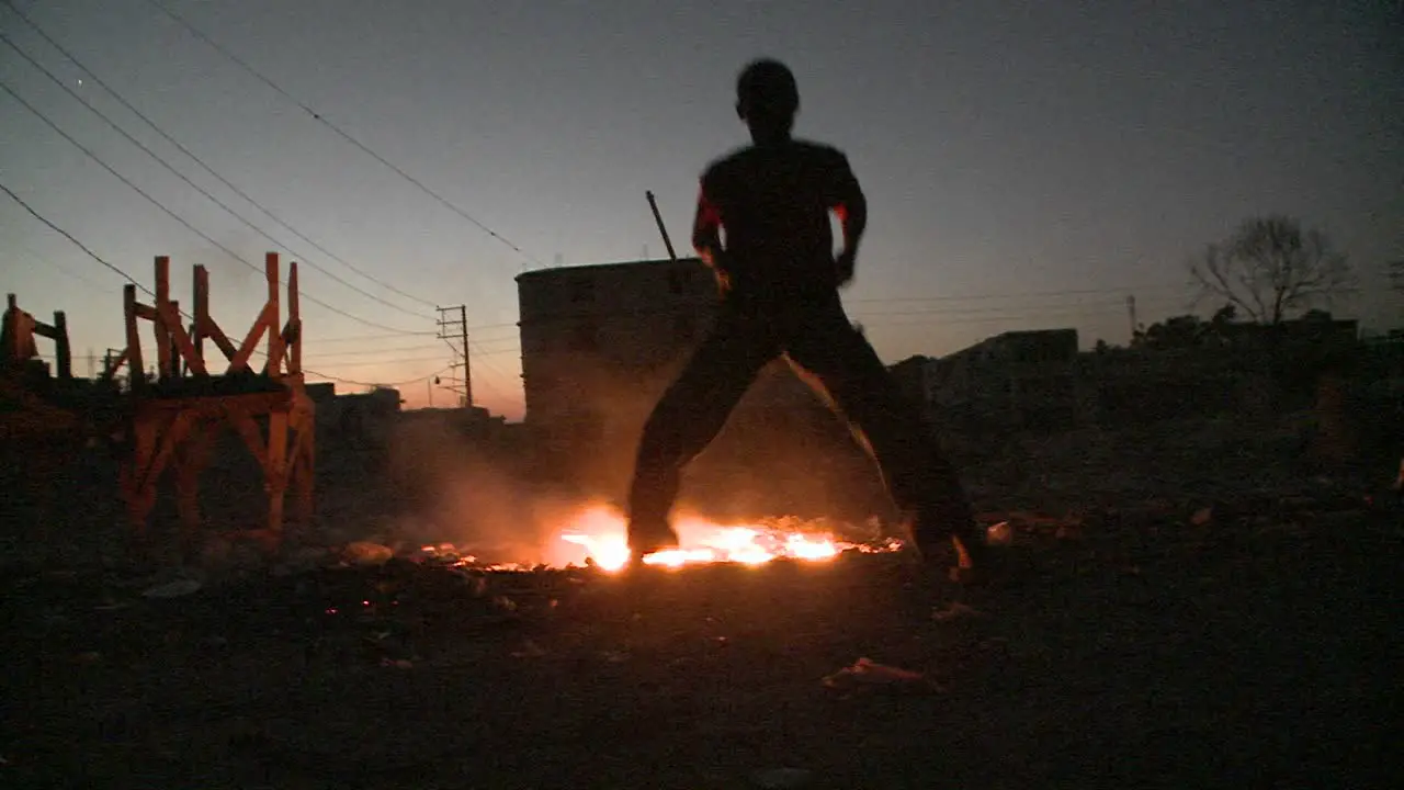 A man dances in silhouette in front of a fire 1