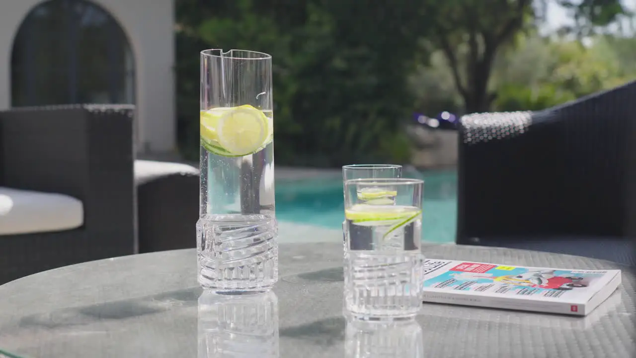 Slow revealing shot of garnished refreshments sitting by the private pool