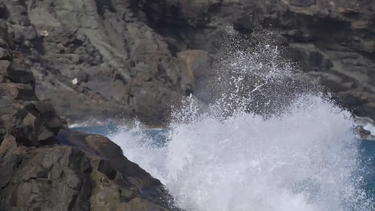 Waves crashing and splashing into rocks in slow motion