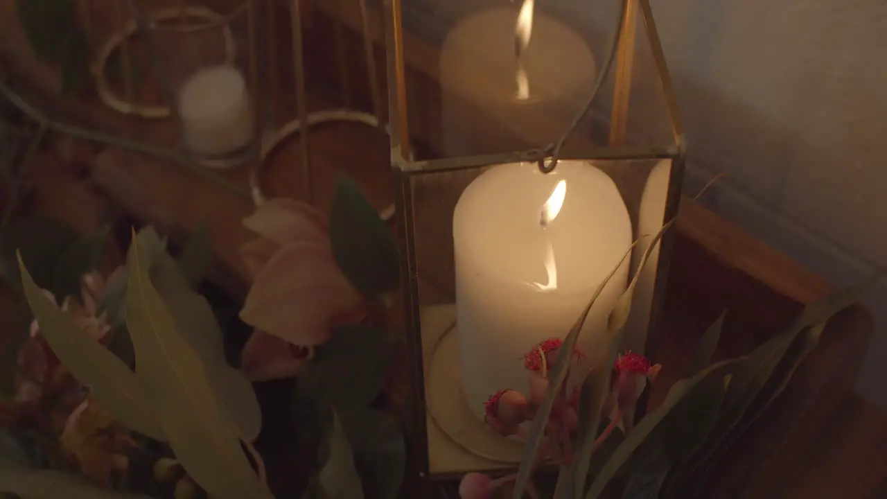 candle burning documentary b-roll of moody storm candle glass with decorative flowers wick burning a flame in reflections